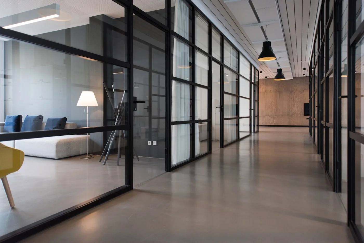 Shared office spaces opening onto a bright, glass-lined corridor